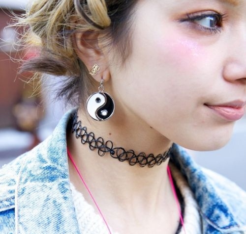 Young woman in the 90s with yin-yang earrings and a choker necklace