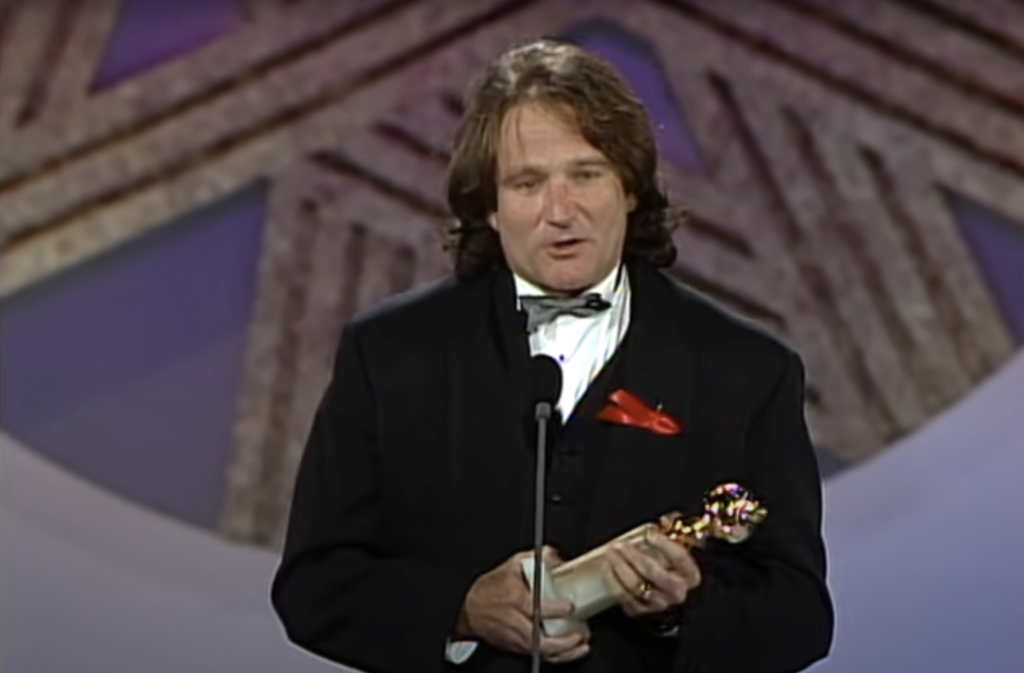 Robin Williams with long hair accepting an award