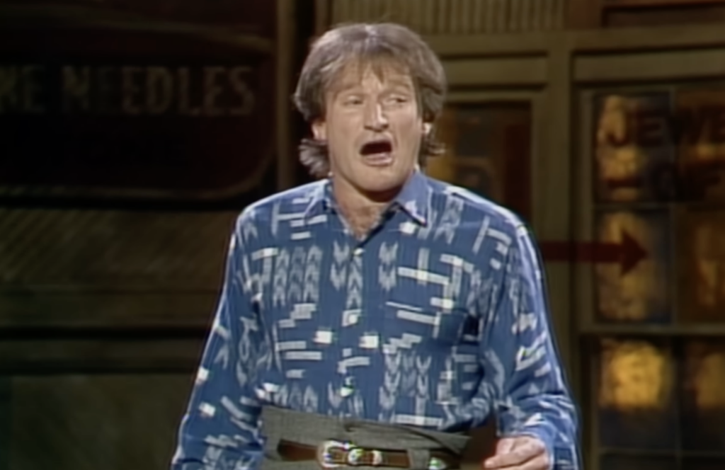 Robin Williams in a blue shirt on stage