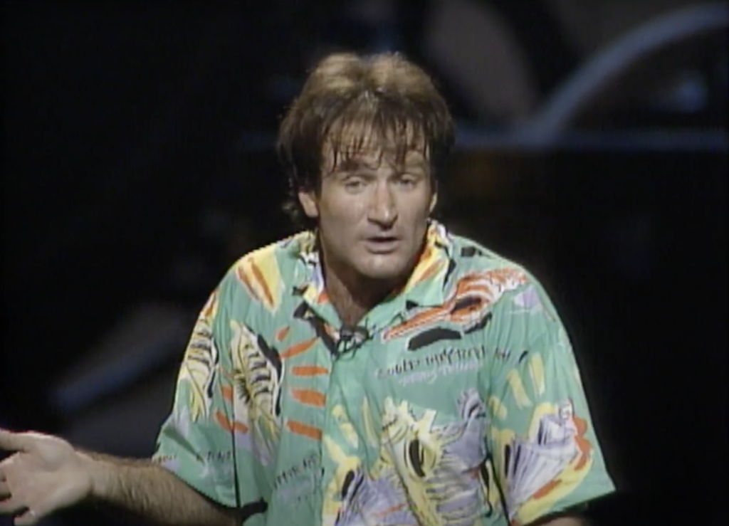 Robin Williams telling a joke in a hawaiian shirt 