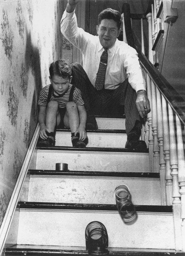 Richard T James and his son playing with three slinkys on a staircase