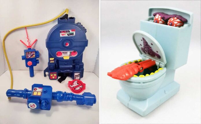 A set of vintage Ghostbusters collectibles: a blue proton pack, two ghost-catching devices with stickers, a Ghostbusters badge, and a light blue toilet with an open lid revealing a toy ghost and purple slime.