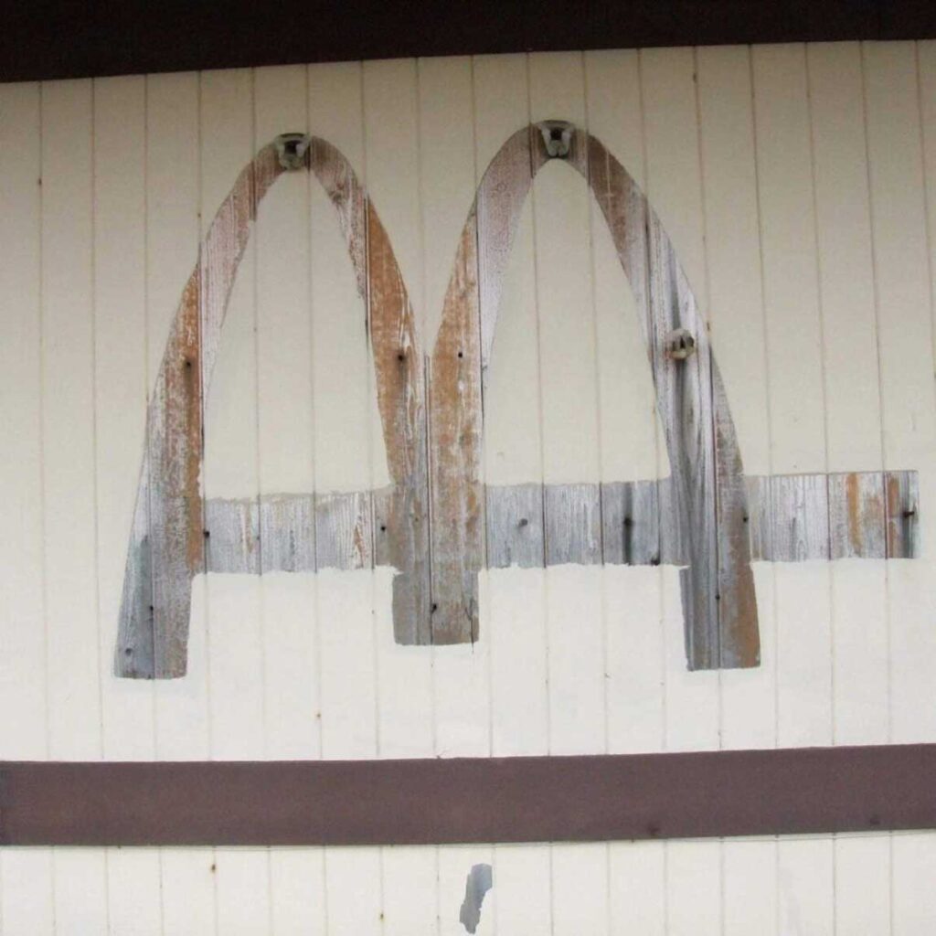 Faded and deteriorated remains of what used to be two arches on a wooden surface, with visible signs of rust and weathering.