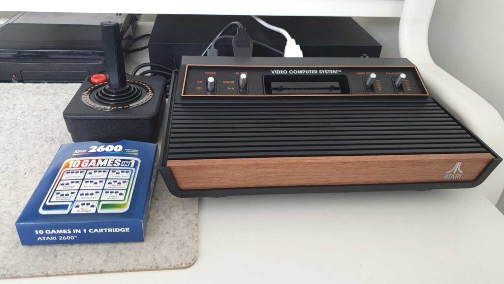 An Atari 2600, one of the best-selling video game consoles, comes complete with a joystick and a 10 Games in 1 cartridge. The console's iconic wood grain finish adds nostalgia, while the nearby cartridge box promises endless entertainment.