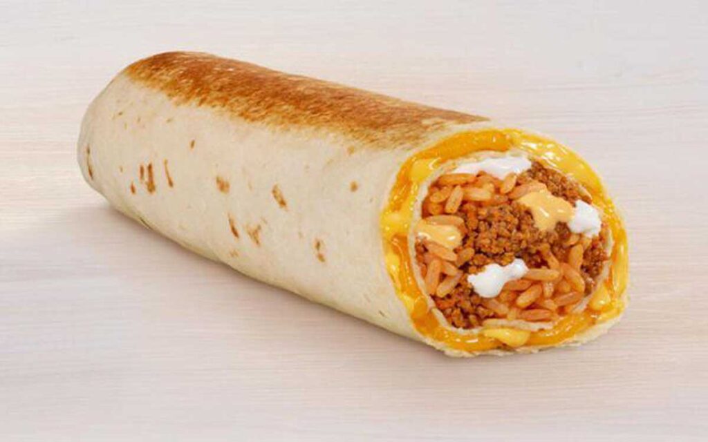 A burrito reminiscent of discontinued Taco Bell menu items features melted cheese, seasoned ground meat, rice, and a dollop of sour cream, wrapped in a lightly toasted flour tortilla on a light wooden surface.