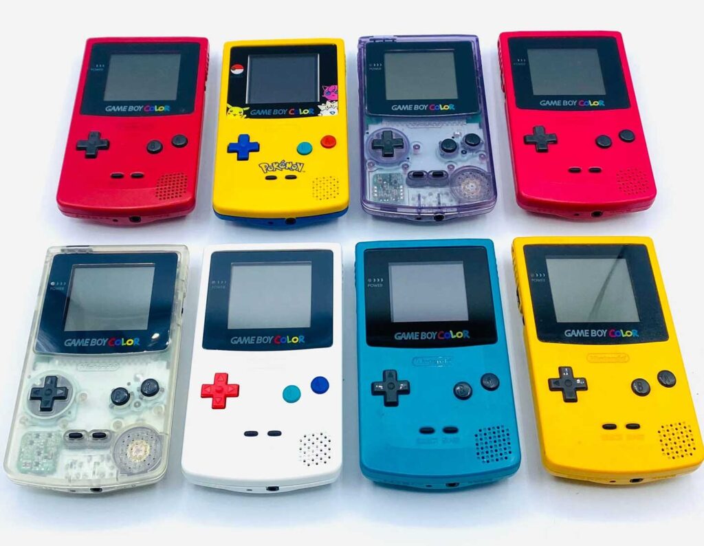 A collection of eight best-selling Game Boy Color handheld consoles in various colors, including purple, red, blue, yellow, and white. Some feature Pokémon designs. These iconic devices are arranged in two rows on a white background.