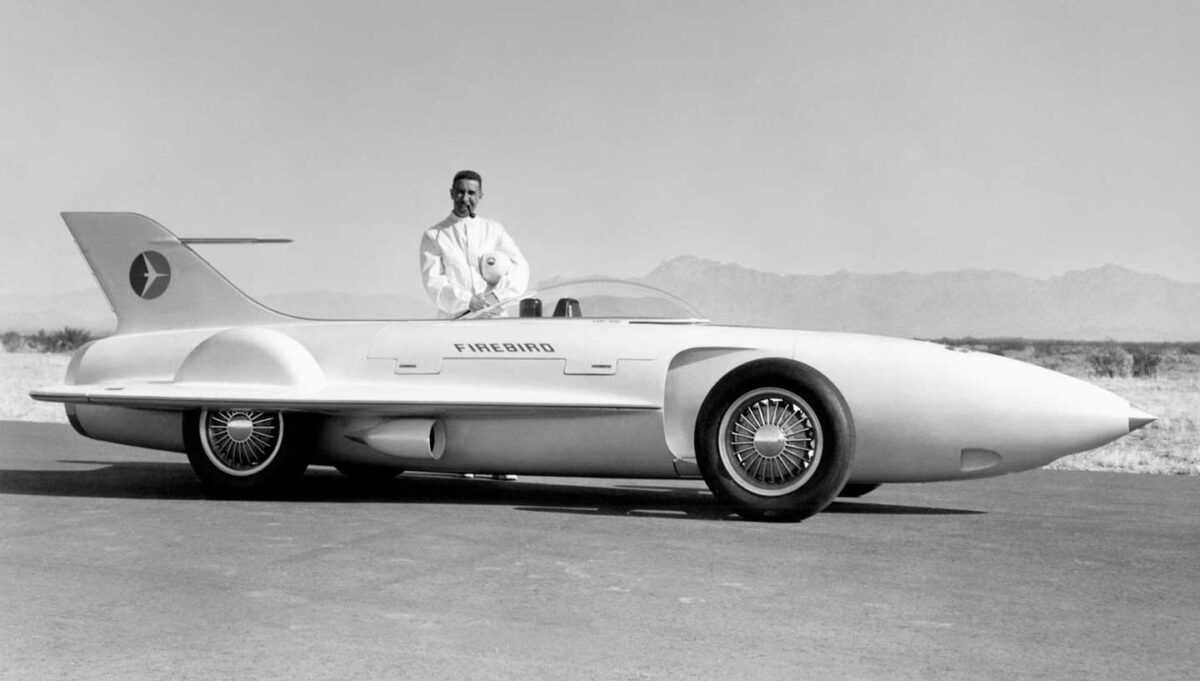 Vintage concept cars - A black and white photo of a man standing behind a General Motors Firebird I (1953) concept car