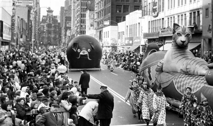 Vintage photos of Gimbel's Parade - A look down a crowded street that watches on as floats of a cat and a pig pass by in Philadelphia