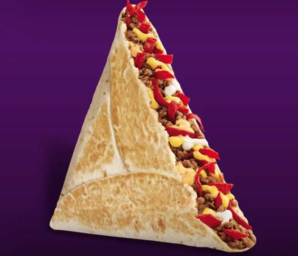 A folded tortilla forming a triangular shape, filled with ground beef, melted cheese, sour cream, and red tortilla strips—a nostalgic nod to discontinued Taco Bell menu items—displayed against a purple background.