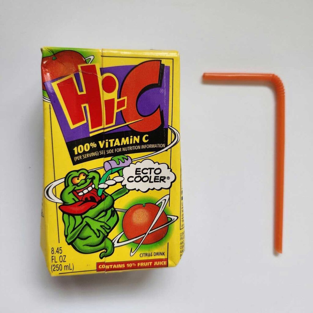 A vintage Hi-C Ecto Cooler juice box featuring a cartoon ghost design, sitting next to an orange bendy straw. This nostalgic gem from the world of discontinued snacks from the 90s showcases 100% Vitamin C and a playful, colorful Citrus Drink layout.