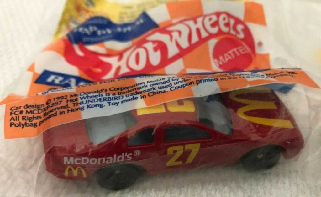 A packaged Hot Wheels toy car from McDonalds, featuring a red car with 27 and McDonalds logos. The packaging shows the Hot Wheels and McDonalds branding.