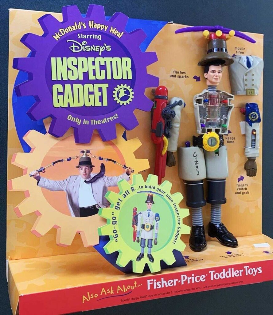 Inspector Gadget-themed McDonalds Happy Meal toy set featuring a figure with extendable arms and accessories. The packaging is colorful with gears and promotional text for Disneys movie. Includes Fisher-Price Toddler Toys mention at the bottom.