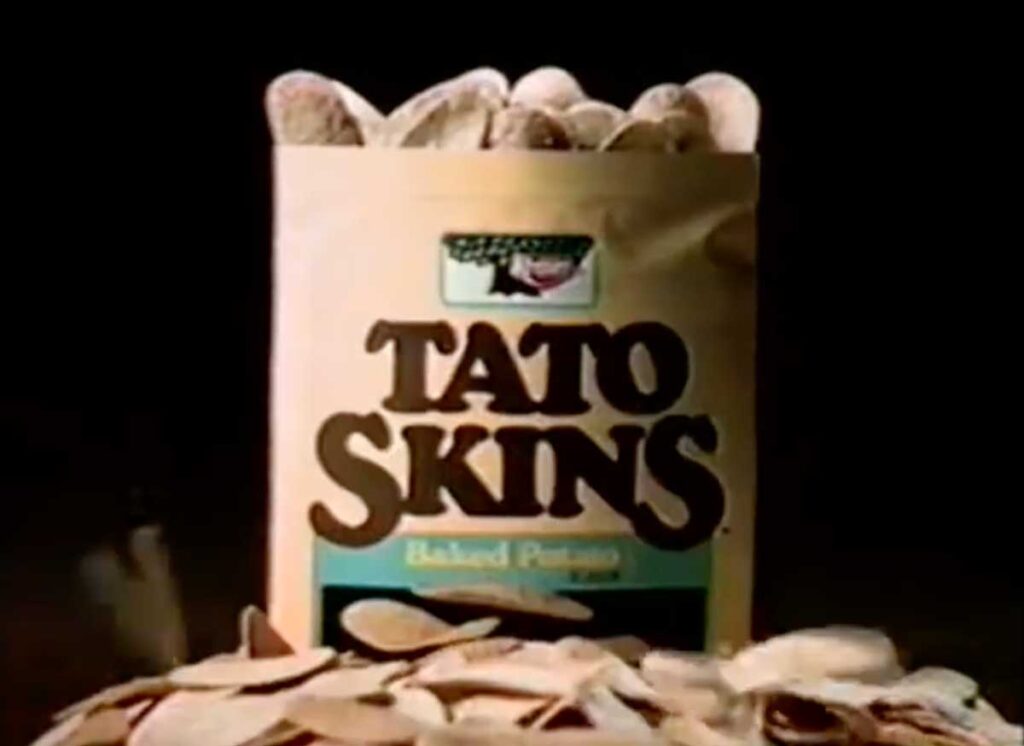 A bag of Tato Skins Baked Potato Snacks, reminiscent of the beloved discontinued snacks from the 90s, sits open with chips spilling out. The packaging flaunts a vintage brown and green design adorned with a potato illustration and the brand name boldly showcased.