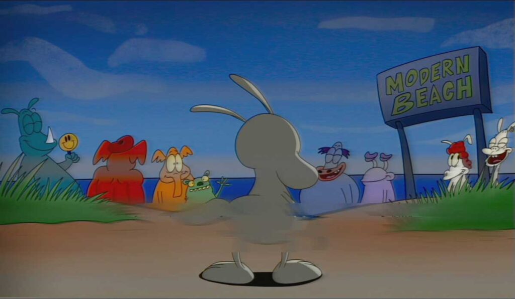 A cartoon scene depicting a gray character on a sandy path approaching a sign that reads Modern Beach. Several colorful animated creatures stand on either side, smiling and observing the character. The sky is blue with a few clouds.