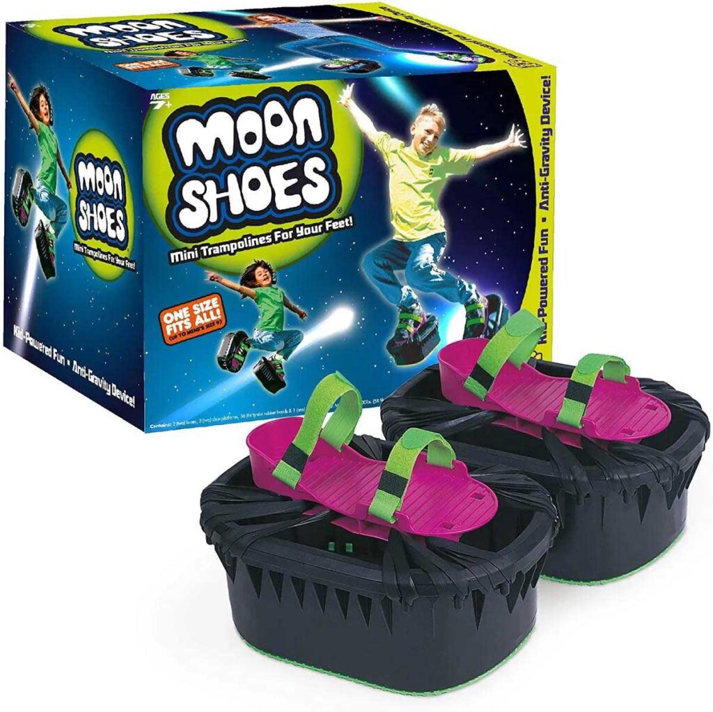 Image of Moon Shoes packaging with a pair of black and pink bouncy shoes in front. The box shows a child jumping with excitement, highlighting the tagline Mini Trampolines for Your Feet! and One Size Fits All! on a starry background.