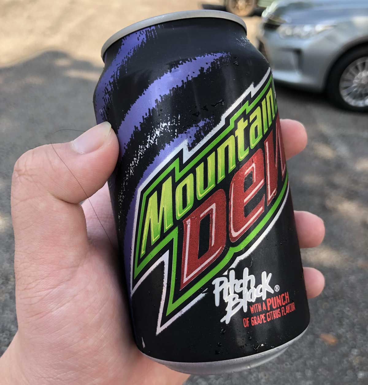 Hand holding a can of Mountain Dew Pitch back