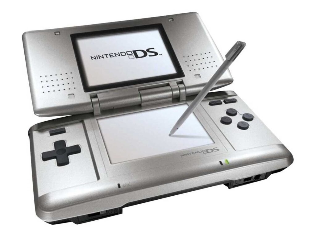 A silver Nintendo DS handheld game console, one of the best-selling video game consoles, with its dual screens open. The top screen displays the iconic Nintendo DS logo, while the lower touchscreen hosts a resting stylus. The console features control buttons and a directional pad.