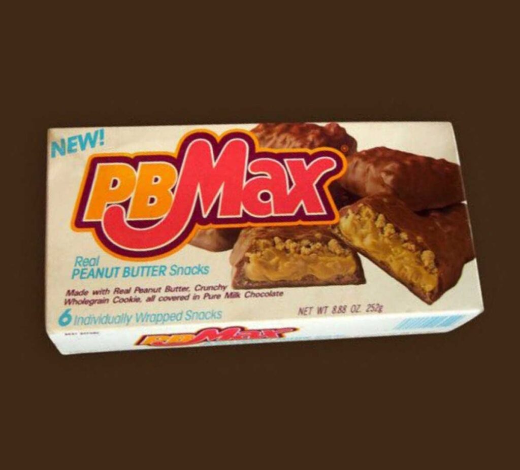 A box of PB Max snacks, reminiscent of popular discontinued snacks from the 90s, features chocolate-covered peanut butter bars with crunchy cookie centers. The package highlights Real Peanut Butter and notes 6 Individually Wrapped Snacks with a net weight of 8.8 oz (252g).