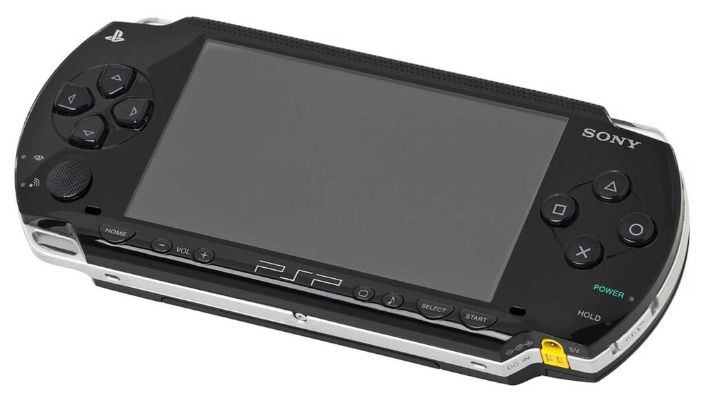 A black Sony PSP, one of the best-selling video game consoles, features a wide screen with control buttons on both sides and various operational buttons like volume and power. The PSP logo is prominently displayed below the screen.