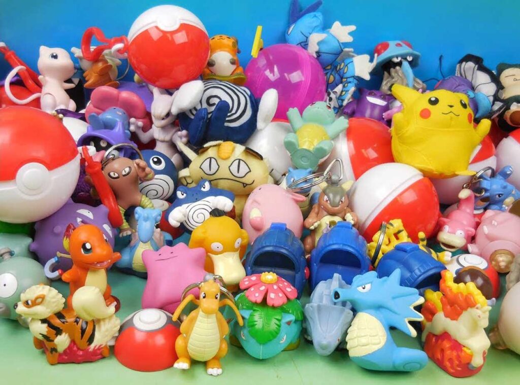 A colorful collection of various Pokémon toys and figures, including Pikachu and Charmander, alongside Poké Balls in the background on a blue surface.