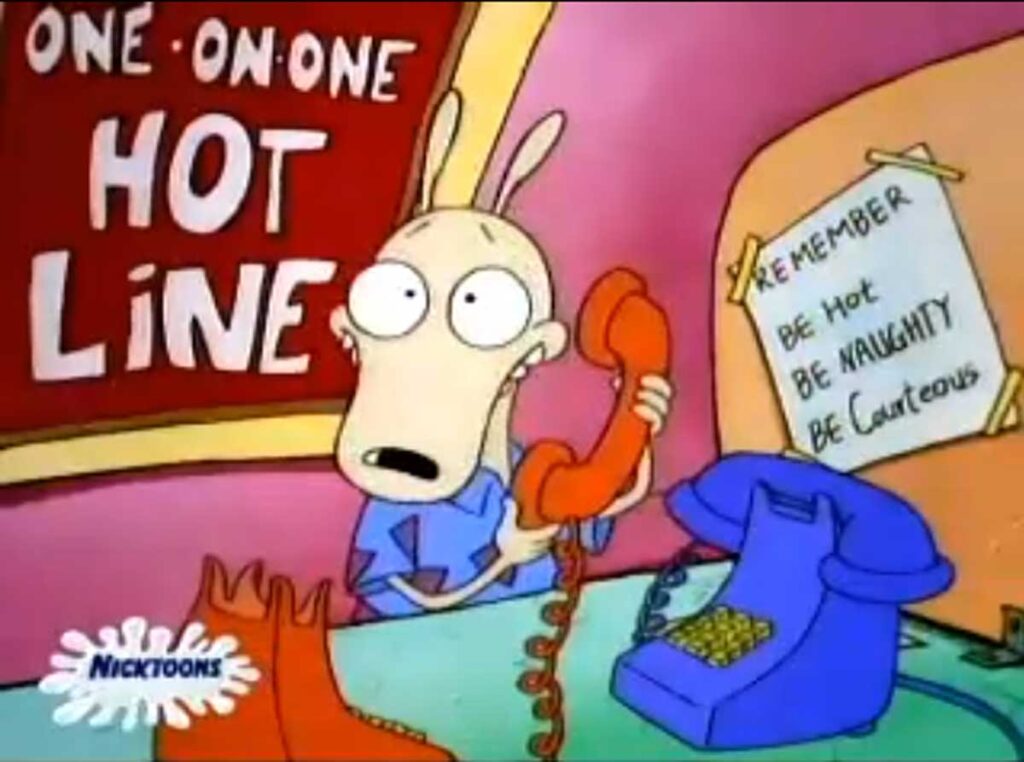 A cartoon character stands at a desk labeled One-On-One Hot Line, holding a red phone with a surprised expression. A sign on the wall reads, Remember: Be Hot, Be Naughty, Be Courteous. Two phones are on the desk.