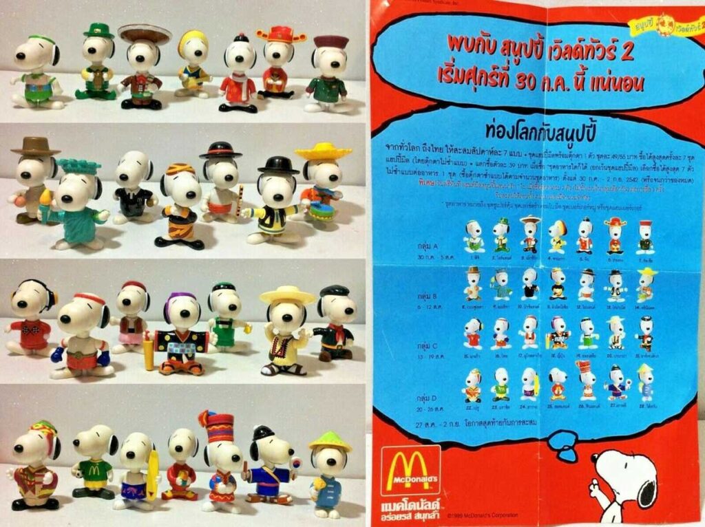 Image shows a collection of Snoopy figurines in various cultural outfits. Theyre displayed on the left, with a red and blue McDonalds promotional background on the right, featuring text in Thai and small images of each figurine.