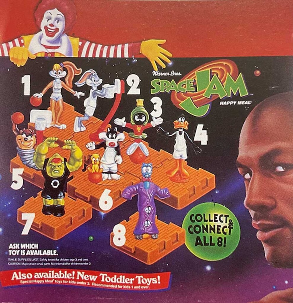 A vintage Space Jam Happy Meal advertisement featuring a set of collectible toys. The image shows cartoon characters on numbered platforms, surrounded by colorful graphics. Ronald McDonald is in the background. Text mentions collectible features.