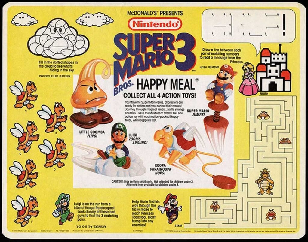 A vintage McDonalds Super Mario Bros. 3 Happy Meal tray liner featuring four collectible action toys: Little Goomba, Luigi, Mario, and Koopa Paratroopa. The liner includes games, puzzles, and vibrant cartoon illustrations.