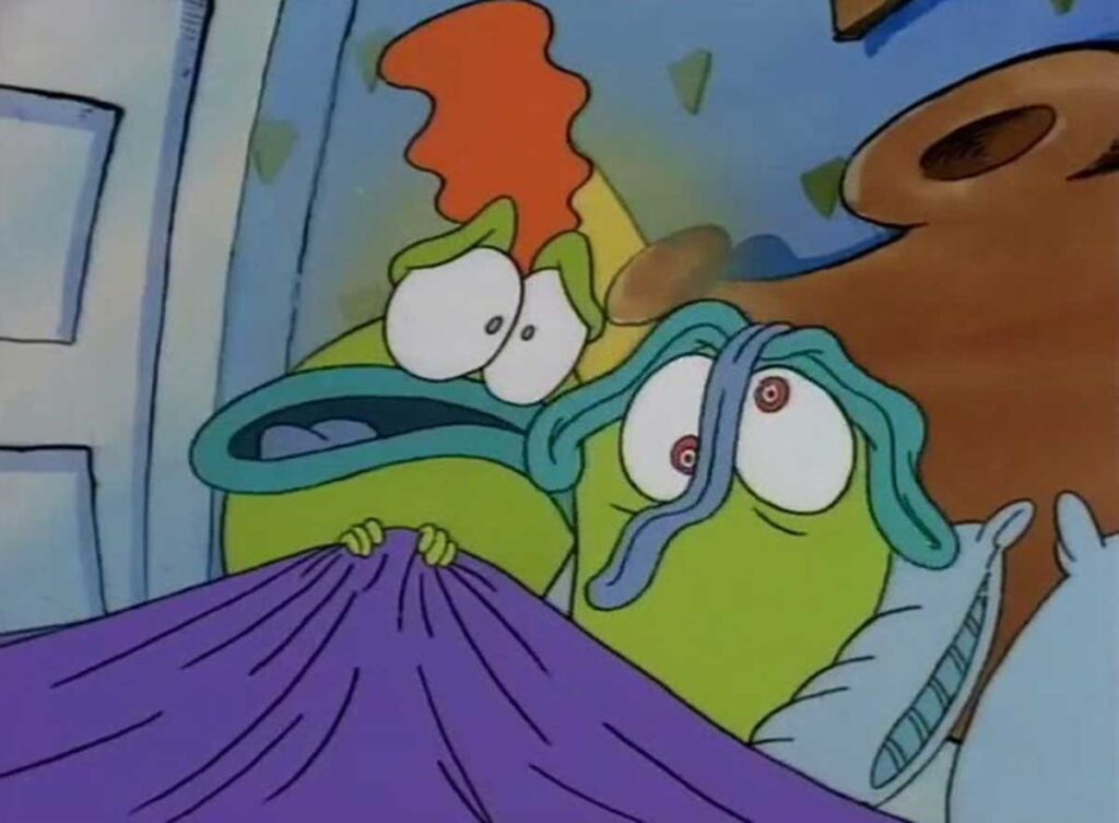 Two animated green characters with anxious expressions are peeking over a purple blanket. One has a red mohawk and the other has blue tentacle-like hair and a large, red eye on its head. Theyre in a room with a white door and a wooden headboard.