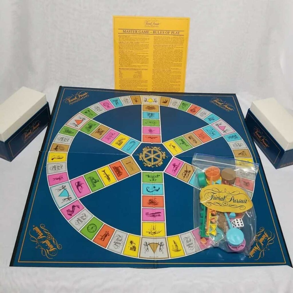 80s board games - A Trivial Pursuit board game with a circular track is set up. The board features colorful question categories. Game pieces, dice, and a rulebook are included. Two white boxes are placed on either side of the board.