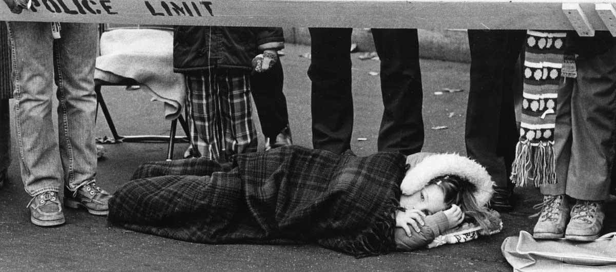 Little girl in 1978 laying on the ground watching the parade