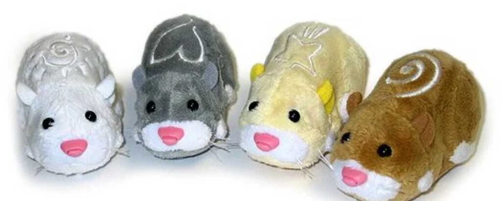 Four plush toy hamsters in white, gray, yellow, and brown, each with embroidered designs on their backs and pink noses. They are arranged side by side against a white background.