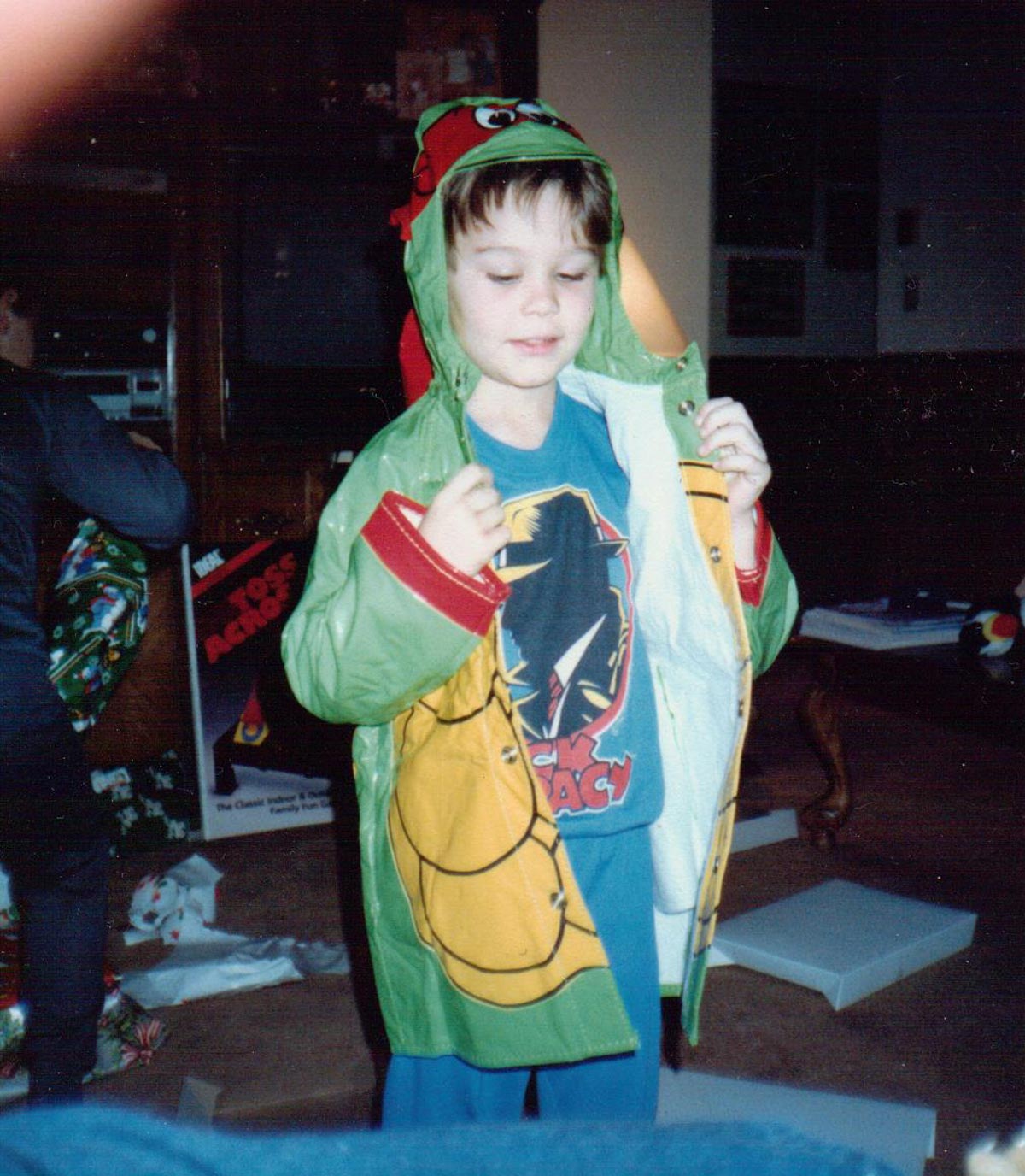 Kid on Christmas morning in the 90s trying on his new Teenage Mutant Ninja Turtle jacket over his Dick Tracy shirt.