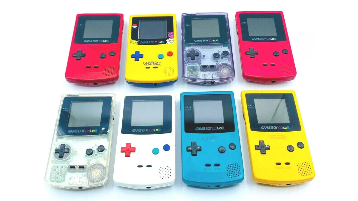 A collection of eight colorful Game Boy Color handheld consoles arranged in two rows. The consoles are in various colors: red, yellow, clear, blue, and teal. Each console has a front screen and control buttons.