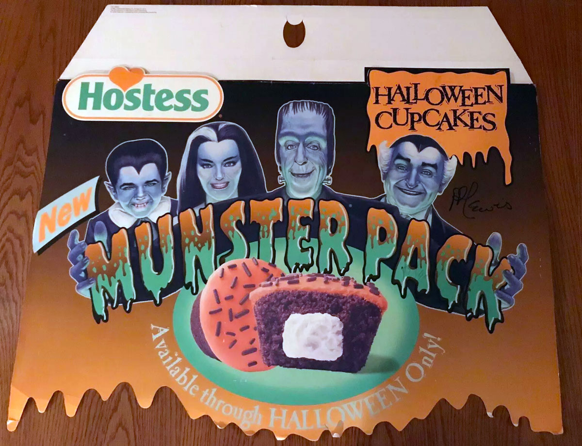 A Halloween-themed Hostess advertisement featuring spooky characters resembling classic monsters above text that reads New Munster Pack. It showcases Halloween cupcakes with orange icing and chocolate sprinkles.