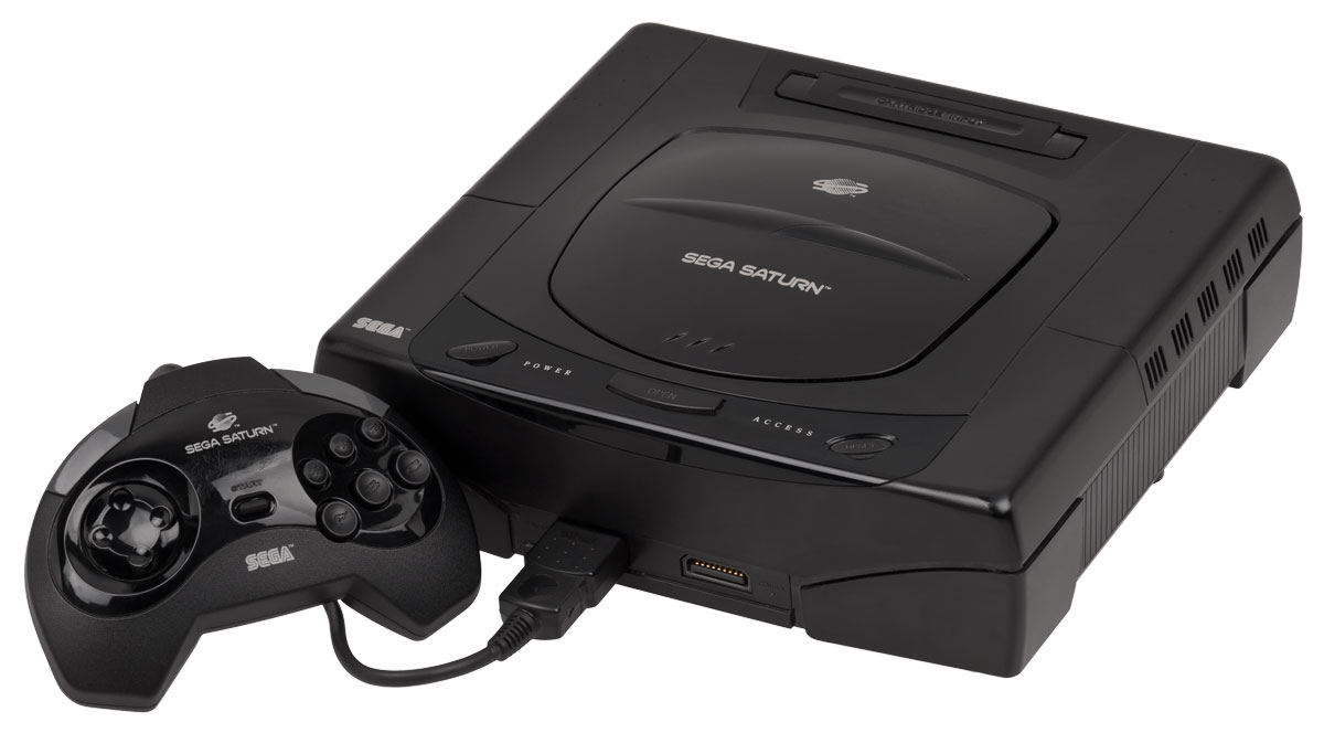 A black Sega Saturn gaming console with its matching controller connected. The console has a sleek design with the Sega Saturn logo on top. The controller features a joystick and multiple buttons.