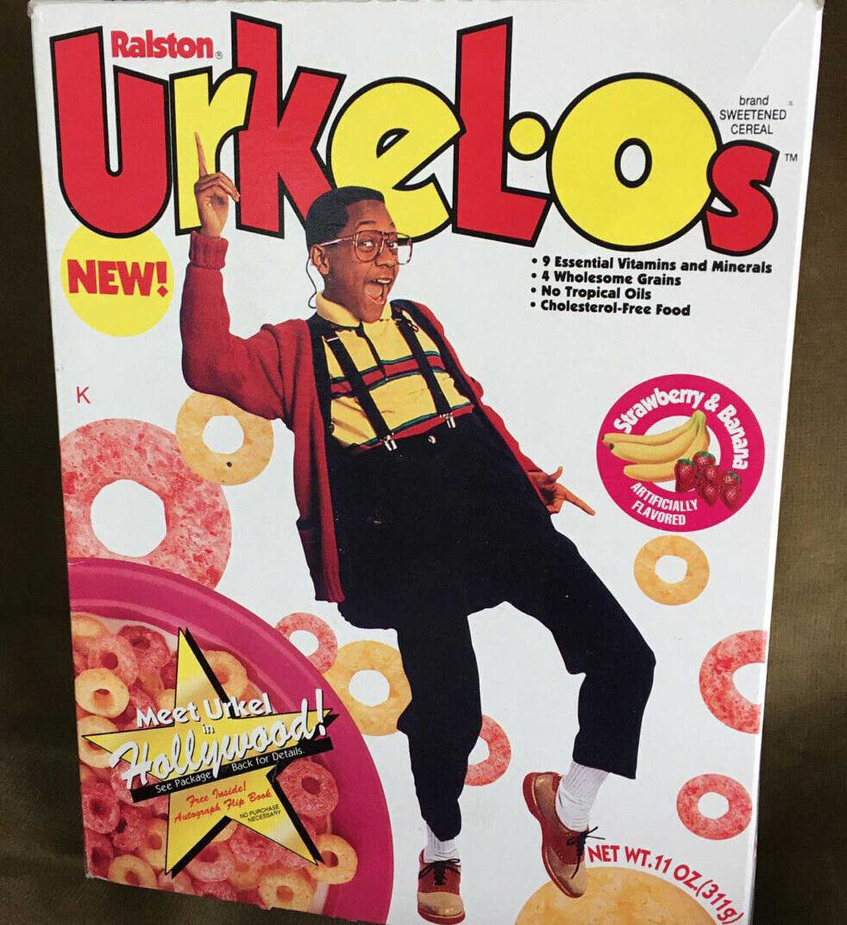 The cereal box, spotlighting the vibrant Urkel-Os, presents a cartoonish image of a person in a red sweater and suspenders joyfully jumping. This breakfast cereal boasts delightful strawberry-banana flavor along with essential vitamins and other nutritional info.