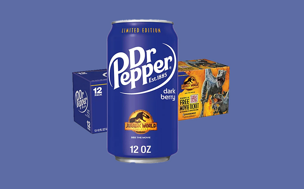 A 12 oz can of limited edition Dr Pepper Dark Berry featuring a Jurassic World design is in front of a box displaying similar branding. The box includes promotional text about a free movie ticket. The background is light blue.