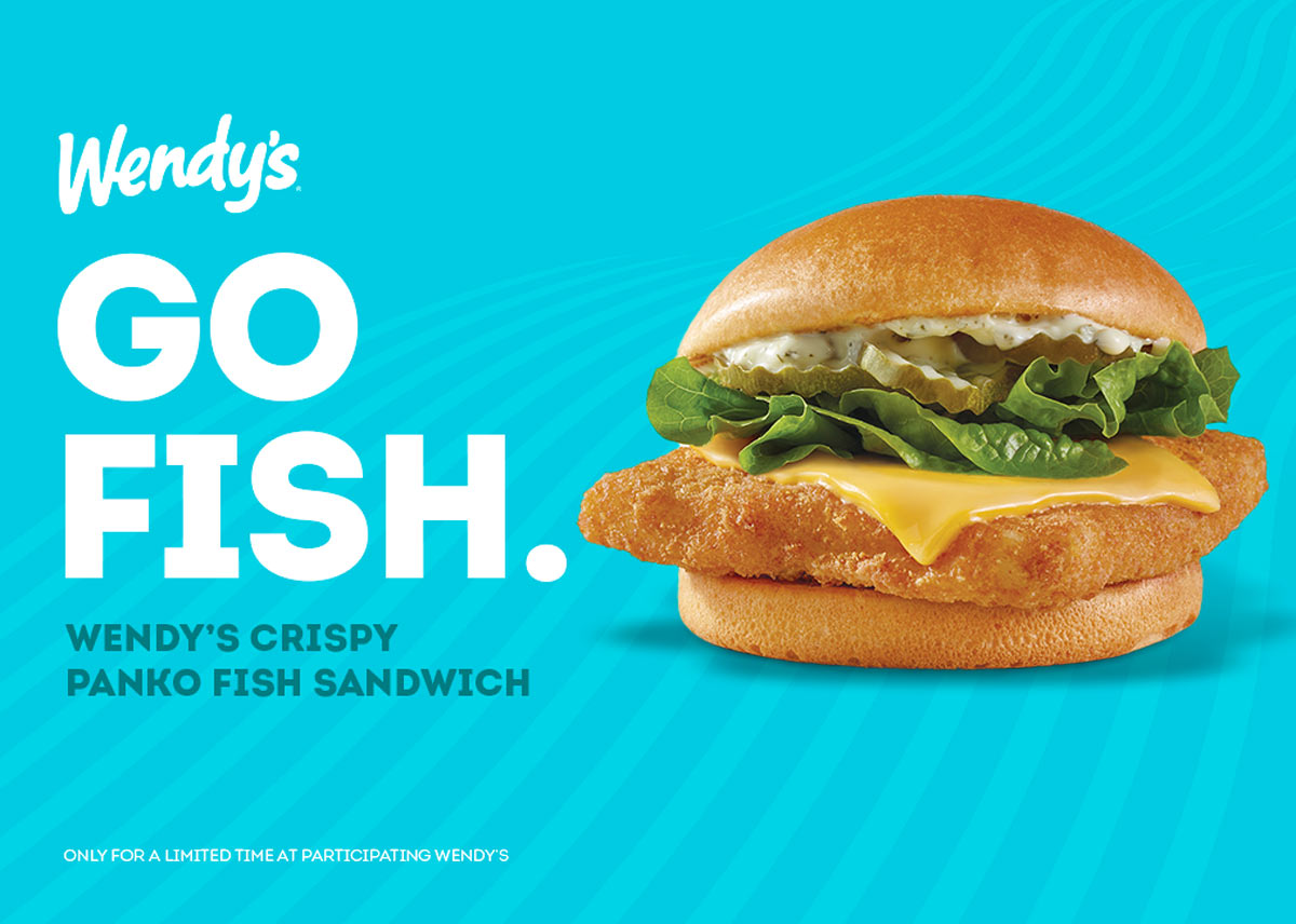 A Wendys advertisement features a Crispy Panko Fish Sandwich with lettuce, cheese, and sauce on a bun against a blue background. Text reads, GO FISH. WENDYS CRISPY PANKO FISH SANDWICH. Only for a limited time at participating Wendys.