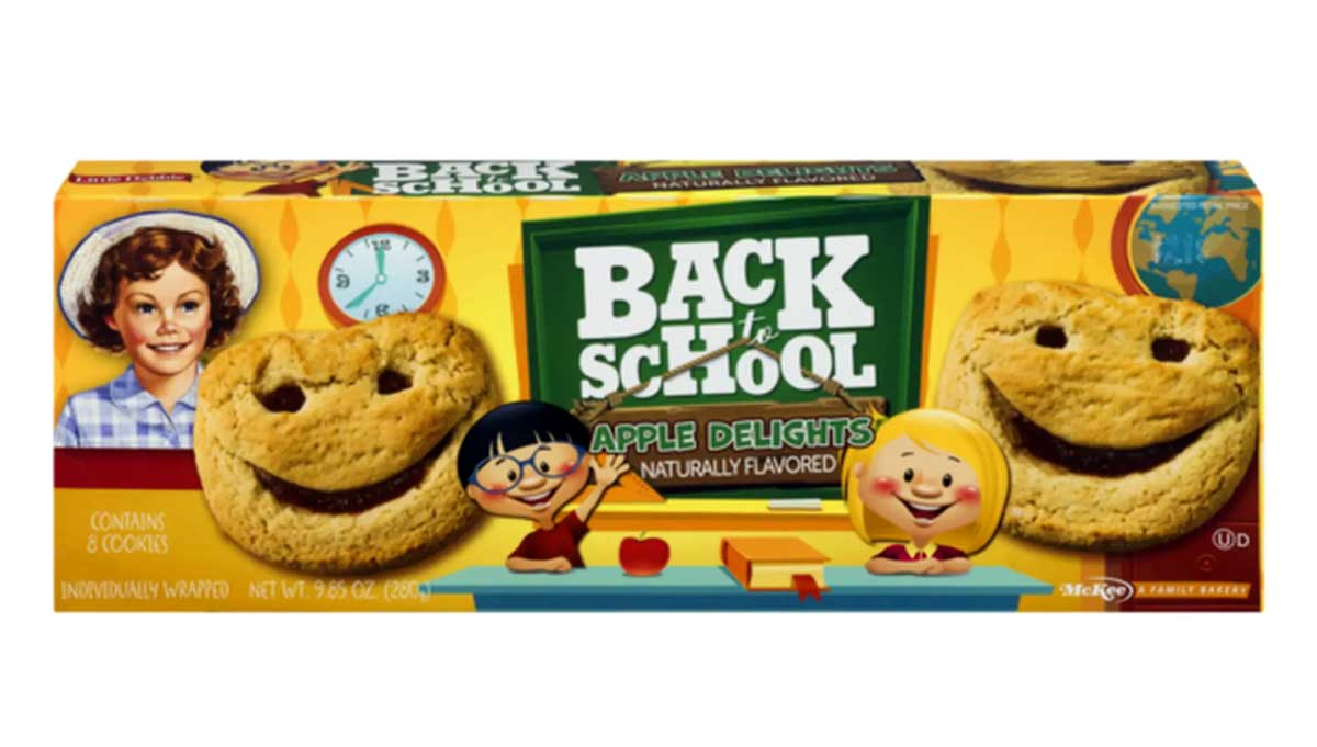 A box of Back to School Apple Delights cookies featuring smiling cookie faces with apple filling. The packaging is colorful with illustrations of children and school-themed graphics. Contains 6 cookies, 10.5 oz.