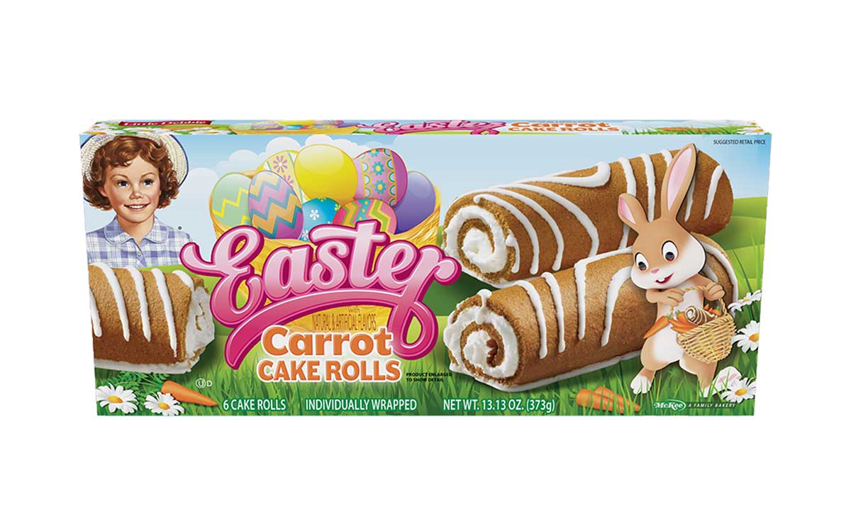 The image shows a package of Easter-themed carrot cake rolls. The box features a cartoon bunny holding a basket and decorated Easter eggs. Inside are individually wrapped cake rolls with cream filling and white icing.