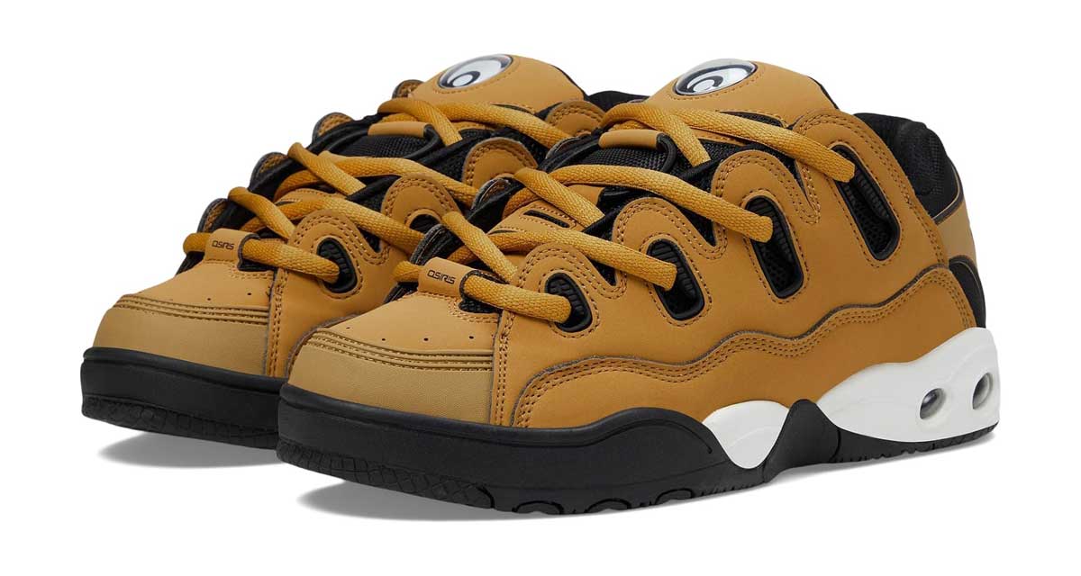 A pair of tan and black skate shoes with thick laces, black soles, and a white midsole with circular detailing near the heel. The shoes have a bold, chunky design and black accents.