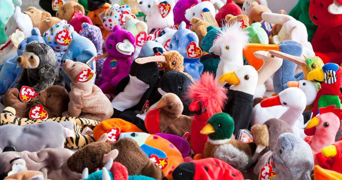 A large collection of colorful Beanie Babies, mostly animal plush toys with Ty tags, are piled together, featuring birds, bears, and other creatures.
