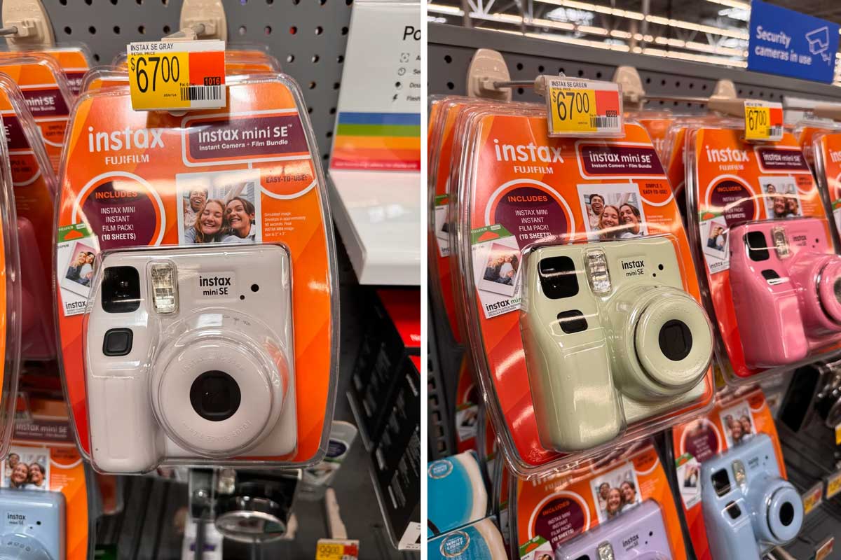 Instax Mini SE instant cameras in pink and green are displayed in plastic packaging on a store shelf. Each is priced at $67.00 and labeled with promotional details on the orange packaging.