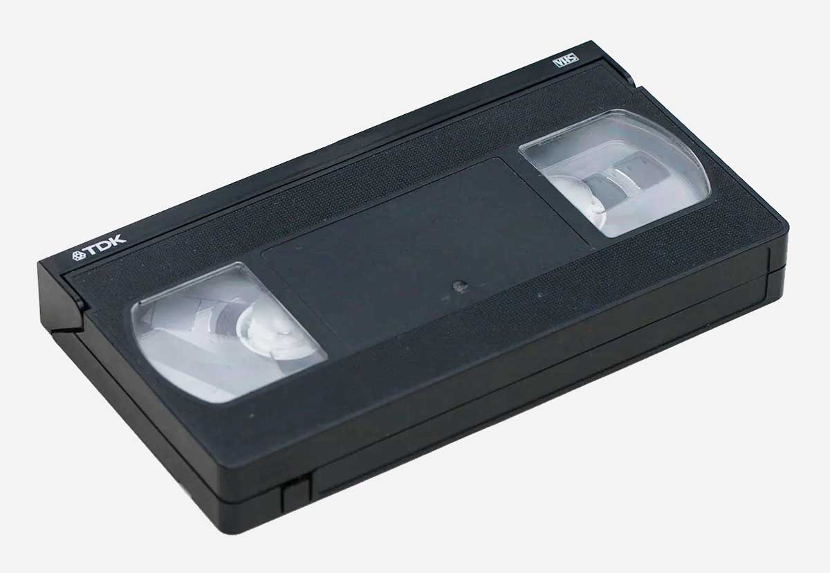 A black VHS cassette tape with clear windows showing the reels inside, resting on a white background.