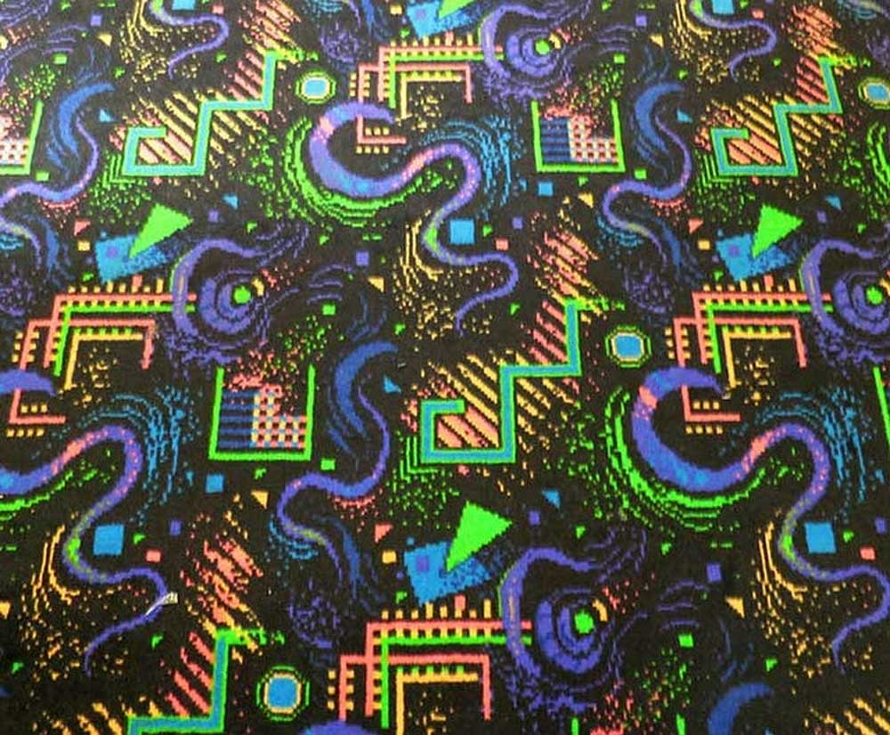 Colorful retro carpet with bold, abstract geometric shapes in neon blue, green, yellow, pink, and purple on a black background, featuring zigzags, swirls, triangles, squares, and dots in a busy 80s or 90s style pattern.