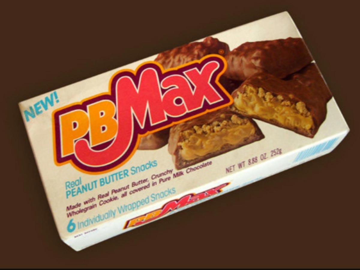 Box of PB Max peanut butter snacks showing the logo, a photo of the chocolate-covered bars with visible peanut butter and crunchy filling, and text highlighting 6 Individually Wrapped Snacks and New! on the packaging.