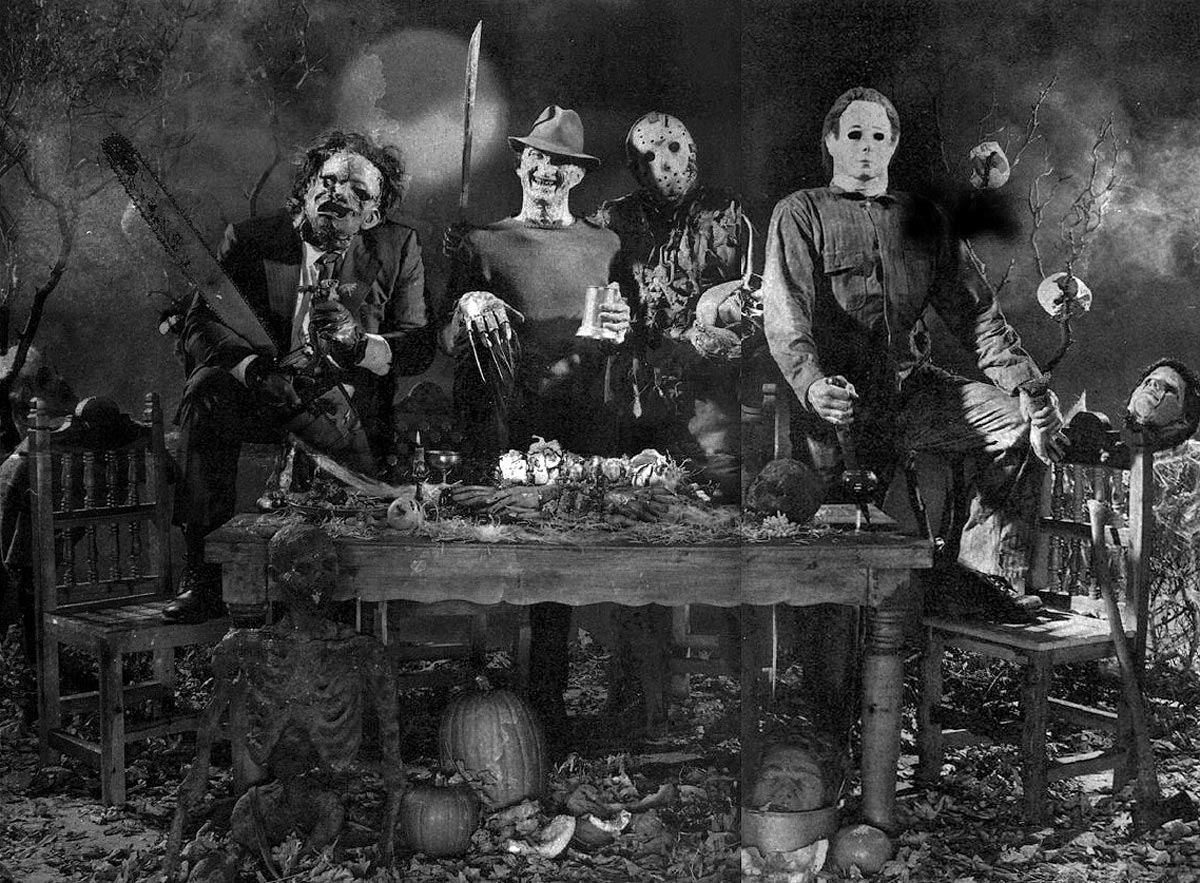 Four people dressed as iconic horror movie villains—Leatherface, Freddy Krueger, Jason Voorhees, and Michael Myers—sit and stand menacingly around a table with Halloween decorations in a dark, eerie setting.