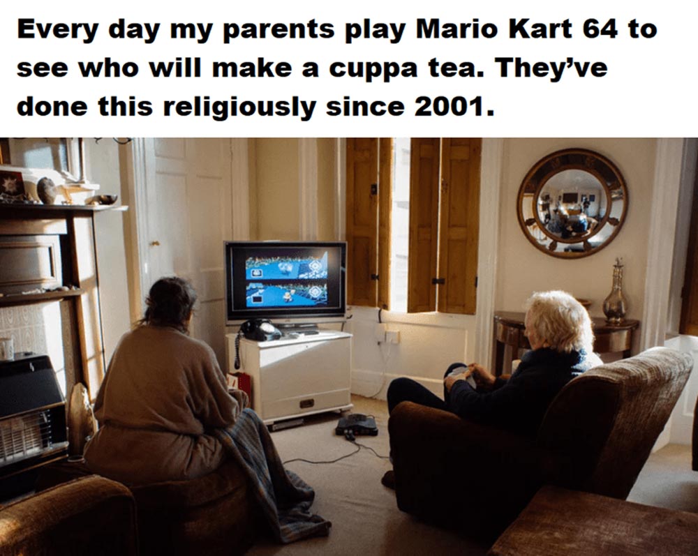 Two older adults sit in a cozy living room, playing Mario Kart 64 on a TV, with text above saying they race daily to decide who makes tea, a tradition since 2001.