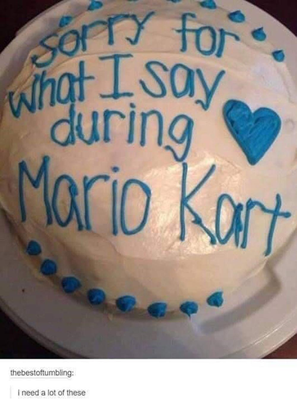 A round cake with white frosting and blue writing that says, Sorry for what I say during Mario Kart, with a blue heart. The cake is on a white plate.